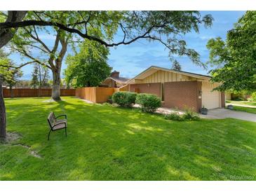 Spacious front yard featuring a well-manicured lawn, mature trees and beautiful landscaping at 7427 W Cedar Cir, Lakewood, CO 80226
