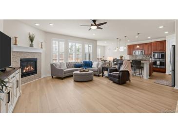 Bright, open living room featuring a fireplace, modern ceiling fan and large windows at 2414 Leafdale Cir, Castle Rock, CO 80109
