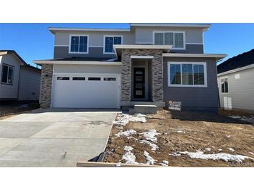 Two-story home with gray siding, stone accents, and a two-car garage at 9122 Telluride Ct, Commerce City, CO 80022