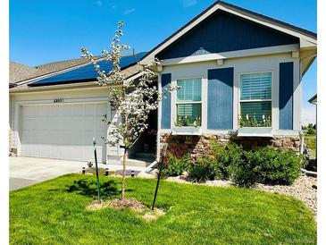 Charming home featuring a well-manicured lawn, solar panels, window boxes, and a two-car garage at 6805 Zebra Grass Ln, Parker, CO 80138