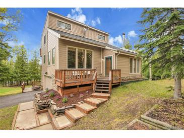 Charming home with tiered deck, landscaped yard and natural light, nestled in a wooded setting against a blue sky at 2654 Sinton Rd, Evergreen, CO 80439