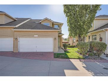 Charming stucco home boasts an attached two-car garage and manicured lawn at 2417 S Racine Way, Aurora, CO 80014