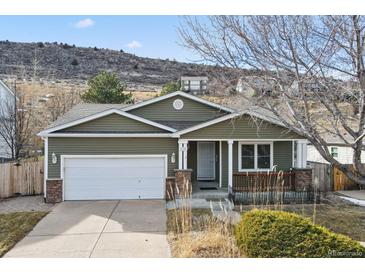 Green house with white garage door and landscaping at 7139 Pine Hills Way, Littleton, CO 80125