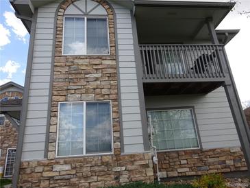 Two-story condo featuring stone accents, a balcony, large windows, and neutral siding at 3271 E 103Rd Pl # 1307, Thornton, CO 80229