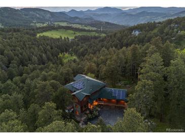 Stunning aerial view of a home nestled in a forest with mountain views and solar panels at 91 Hess Ave, Golden, CO 80401