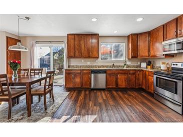 Charming kitchen featuring wood cabinetry, stainless appliances, granite counters, and wood floors at 4774 Coker Ave, Castle Rock, CO 80104