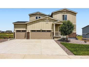 Tan two story home featuring a 3-car garage, stone accents, and well-manicured landscaping at 42830 Ivydel St, Elizabeth, CO 80107