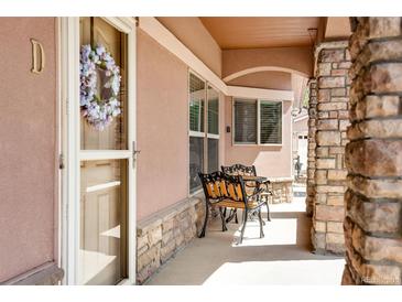 Inviting front porch with cozy seating, stone accents, and a decorative wreath on the door at 15501 E 112Th Ave # 33D, Commerce City, CO 80022