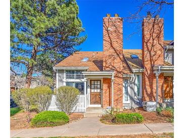 Charming townhome featuring a brick chimney, cozy front porch, and well-manicured landscaping at 2862 W Long Dr # A, Littleton, CO 80120