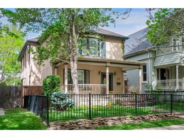 Charming two-story home featuring a covered front porch, black iron fence, and well-maintained lawn at 433 N Ogden St, Denver, CO 80218
