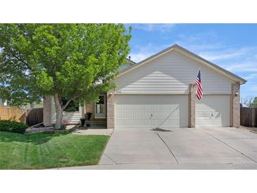 Charming home featuring a two-car garage, well-manicured lawn, and an American flag at 12513 Alcott St, Broomfield, CO 80020