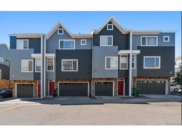 Exterior shot of three townhomes with two-car garages and gray-blue siding, showing symmetry and clean design at 8751 Pearl St # J3, Thornton, CO 80229
