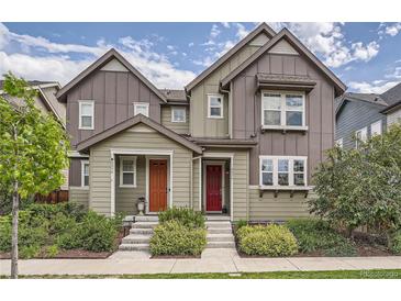 Two-story townhome with gray siding, red and orange doors, and landscaping at 8036 E 53Rd Dr, Denver, CO 80238