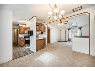 Bright living room features an open floor plan, skylight, and easy access to the kitchen at 1683 Monroe St, Strasburg, CO 80136