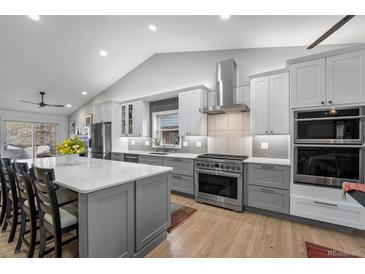 Bright, spacious kitchen with gray cabinetry, stainless steel appliances, and quartz countertops and hardwood flooring at 2687 E 124Th Pl, Thornton, CO 80241