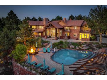 Luxurious backyard featuring a pool, fire pit, lounge chairs, and lush landscaping at 5 Walden Ln, Cherry Hills Village, CO 80121