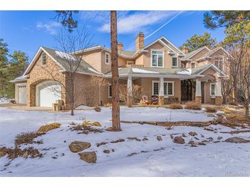 Stunning two-story home with stone and stucco accents, a three-car garage, and a partially snow-covered yard at 17820 Queensmere Dr, Monument, CO 80132