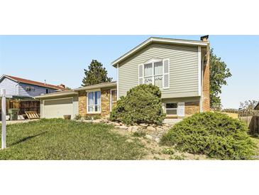 Charming two-story home featuring a brick facade, lush landscaping, and attached garage on a sunny day at 9958 Milwaukee St, Thornton, CO 80229