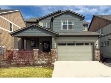 Charming two-story home featuring a covered porch, two-car garage, and manicured front lawn at 476 Hyde Park Cir, Castle Pines, CO 80108