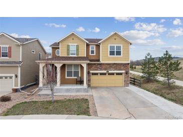 Inviting two-story home with a stone-accented facade, covered porch, and a two-car garage with a concrete driveway at 19760 W 59Th Dr, Golden, CO 80403