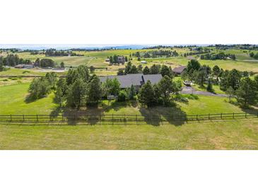 Aerial view of house on large lot with mountain views and wooden fence at 306 Andrea Cir, Parker, CO 80138