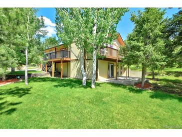 Spacious backyard featuring a two-story house, lush green lawn, and beautiful birch trees at 19235 Wakonda Way, Monument, CO 80132