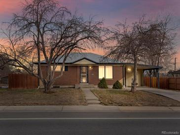 Brick ranch home with mature trees, landscaped yard, and attached carport at 11310 Irma Dr, Northglenn, CO 80233