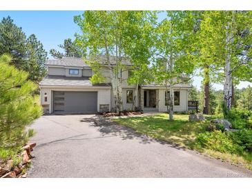 Charming two-story home featuring a two-car garage, mature trees, and manicured landscaping at 2122 Cramner Ct, Evergreen, CO 80439