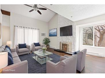 Bright living room features a stone fireplace, high ceilings, hardwood floors, and comfortable seating at 4062 S Atchison Way # 302, Aurora, CO 80014
