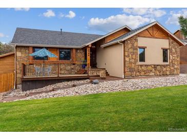Charming home features a stone and wood facade, a deck, and a well-manicured lawn at 8966 Sunridge Hollow Rd, Parker, CO 80134