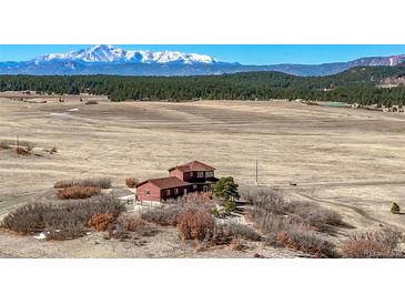 Expansive exterior view of the red home with mountain range in the background at 4586 Best Rd, Larkspur, CO 80118