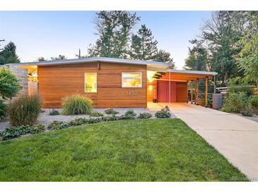 Charming home featuring a modern design, lush lawn, wood details, and covered parking at 1497 S Fairfax St, Denver, CO 80222