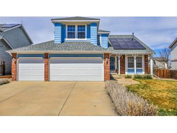 Two-story home with blue siding, brick accents, three-car garage, solar panels and well-maintained lawn and driveway at 19939 E Belleview Ln, Centennial, CO 80015
