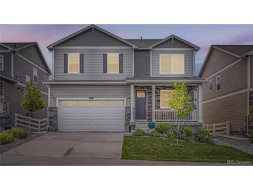 Two story home with a covered porch, a lawn, a two car garage, and grey siding at 4781 Rosette St, Castle Rock, CO 80104