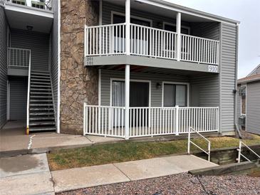 Condo with a stone column accent, white fencing, gray siding and balconies at 910 S Walden St # 101, Aurora, CO 80017