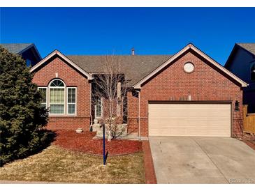 Charming red brick home featuring an attached two-car garage and a well-maintained front yard at 10256 Riverstone Dr, Parker, CO 80134