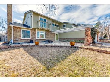 Charming two-story home with a brick and sage green exterior, stone patio, and well-maintained front yard at 7118 W Elmhurst Ave, Littleton, CO 80128