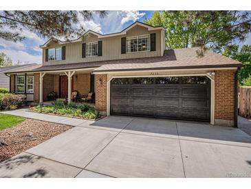 Charming two-story home with a brick facade and a well-manicured lawn and a two car garage at 7655 S Ogden Way, Centennial, CO 80122