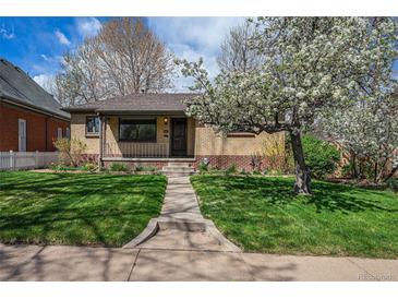 Charming brick home with a lush green lawn and a blossoming tree in the front yard at 1865 S Logan St, Denver, CO 80210