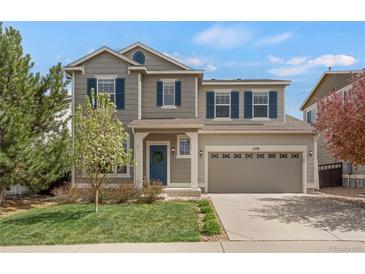 Charming two-story home featuring a manicured lawn, inviting blue door, and an attached two-car garage at 1558 Wandering Way, Castle Rock, CO 80109