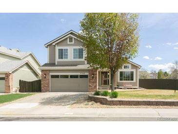 Charming two-story home with a well-manicured lawn, mature tree, and a two-car garage at 9768 Otis Dr, Broomfield, CO 80021