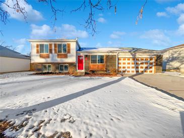 Ranch-style home with red door, attached garage, and snow-covered yard at 481 S Lima Cir, Aurora, CO 80012