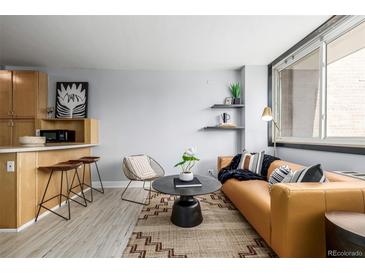 Bright living room with stylish mustard couch and large window at 1196 N Grant St # 204, Denver, CO 80203