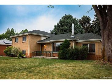 Charming brick home featuring mature trees, green lawn, and a cozy front porch at 2592 S Winona Ct, Denver, CO 80219