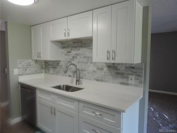 Bright kitchen features white cabinets, stainless steel appliances, and stylish marble backsplash at 9887 E Peakview Ave # F06, Englewood, CO 80111