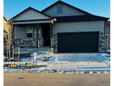 Gray two-story house with a black garage door and landscaping at 4680 Thistle Dr, Brighton, CO 80601