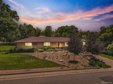 Charming brick home boasts well-maintained landscaping, rock garden, and mature trees under a vibrant sky at 9650 W 35Th Ave, Wheat Ridge, CO 80033