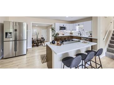 Modern kitchen with stainless steel appliances, white cabinets and quartz counters with center island cooktop at 1880 E 81St Pl, Denver, CO 80229