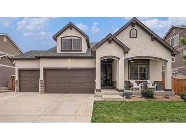Charming home featuring a two-car garage, front porch with seating, and stucco siding accented by stone at 11511 E 118Th Ave, Commerce City, CO 80640