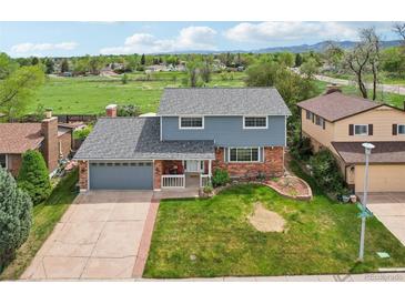 Charming two-story home featuring a well-maintained lawn, a brick facade, and a cozy front porch at 8732 W Arbor Ave, Littleton, CO 80123